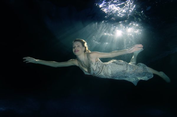 Underwater stills photographer capturing a clothed model in an tank environment